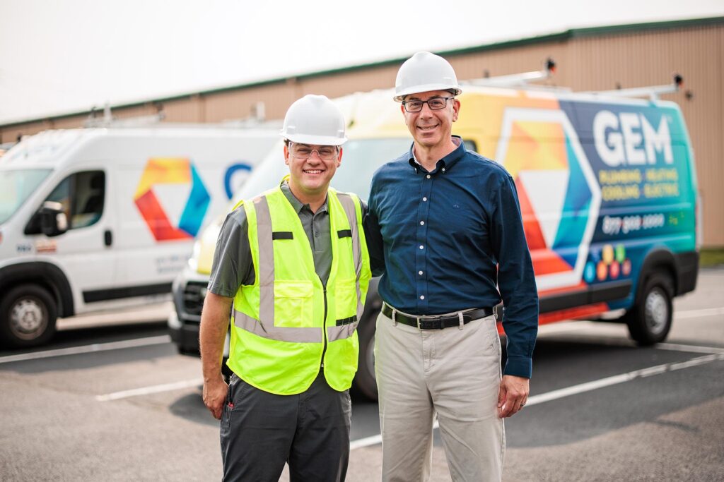 A photo of two GEM commercial technicians in front of a GEM van.
