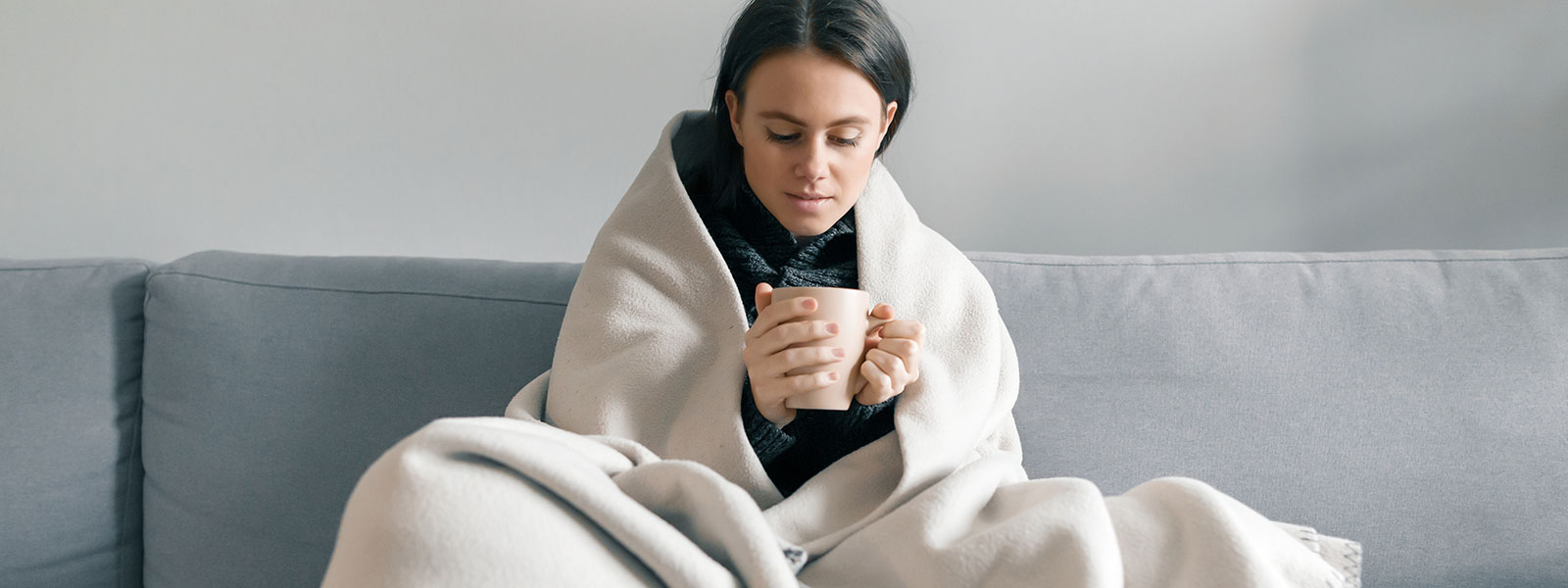 girl wrapped in blanket on couch