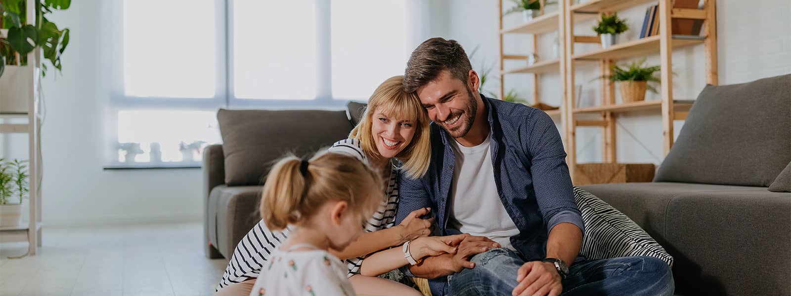 Parents and young daughter playing in a bright living room