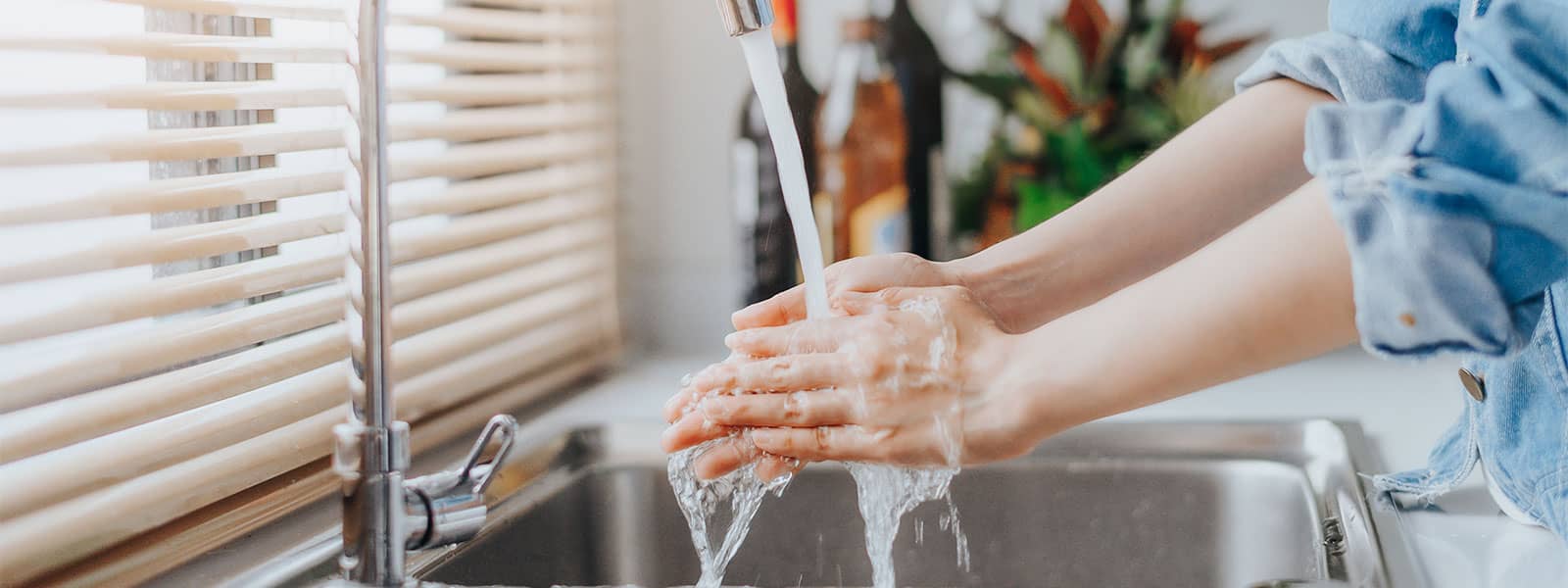 Woman washing her hands in kitchen sink