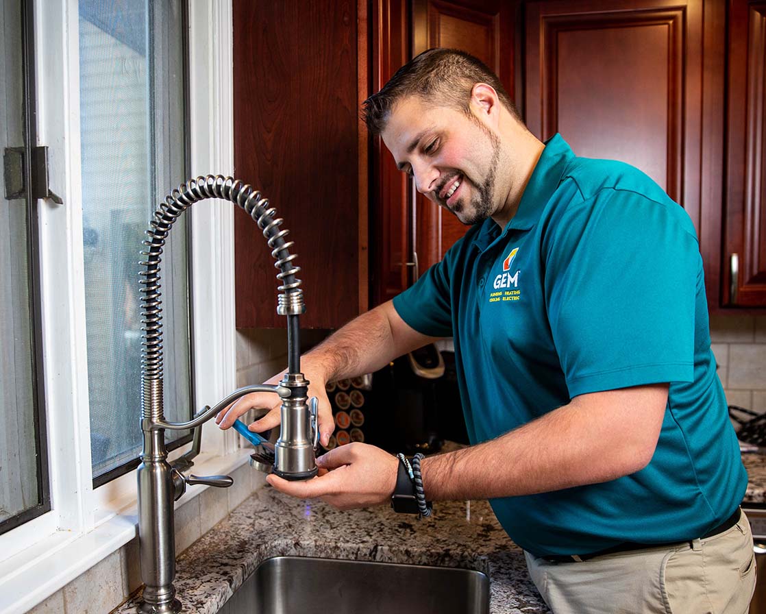 GEM plumber working under kitchen sink