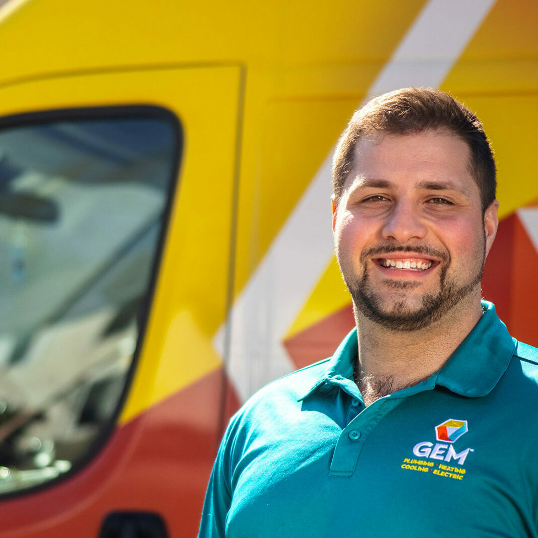 A GEM employee standing smiling in front of a service truck