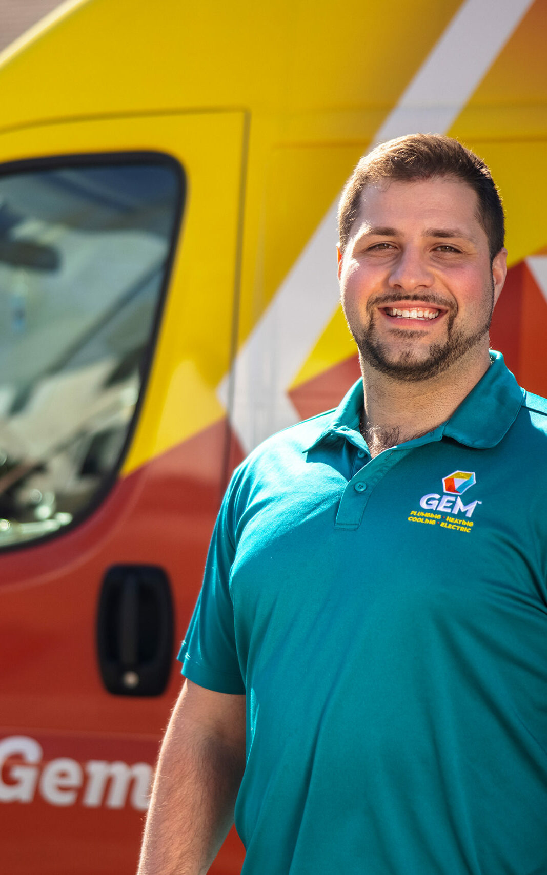 A GEM employee standing smiling in front of a service truck