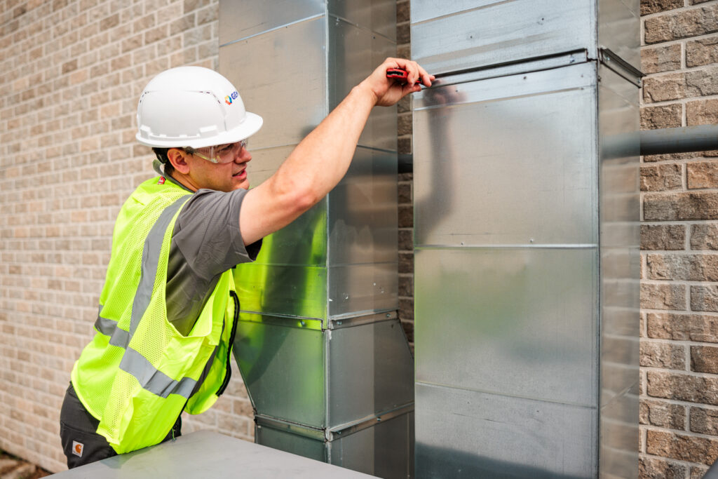 GEM commercial HVAC tech repairing an outdoor HVAC unit vent