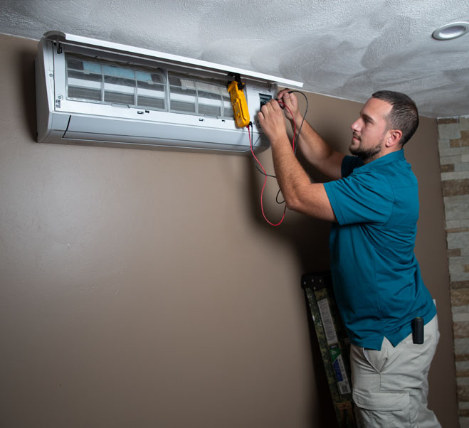 Technician installing a ductless mini split on a wall