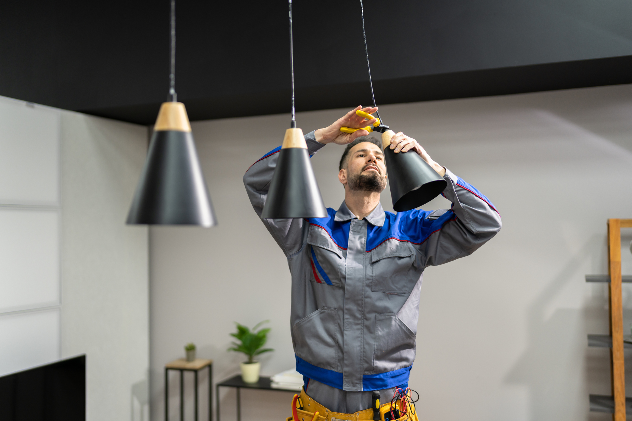 Electrician installing a pendant light in a kitchen.
