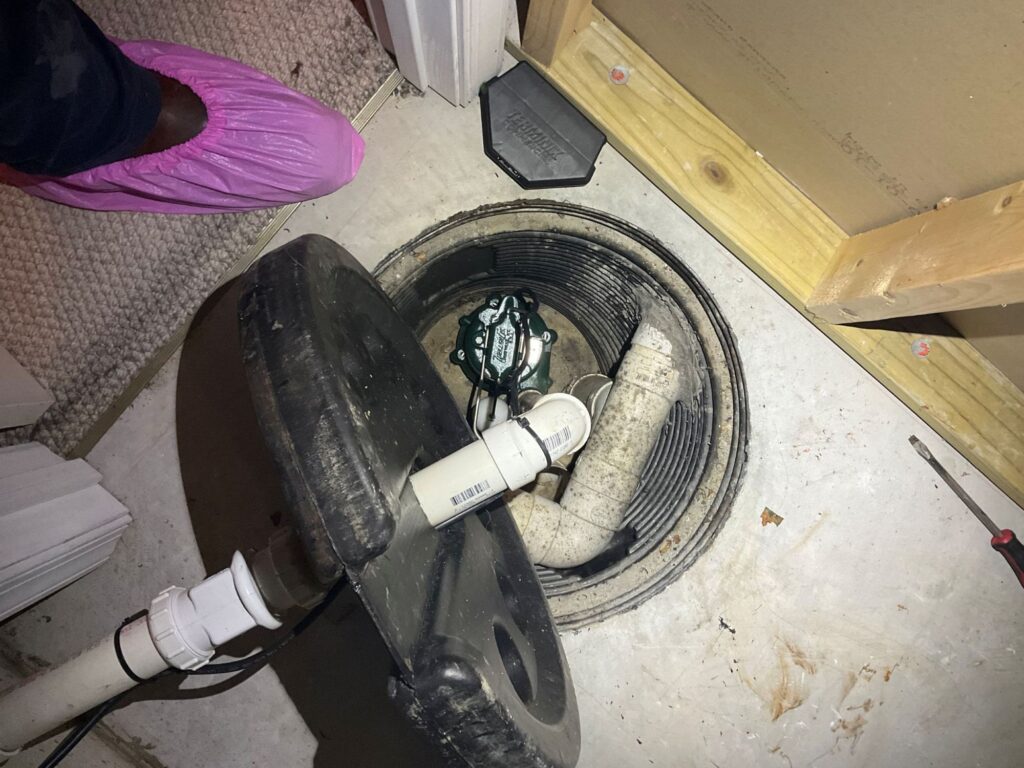 A GEM tech in pink boot covers helps get a sump pump ready for spring snowmelt and rain