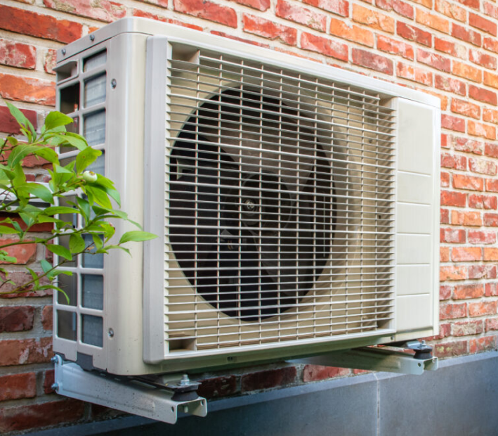 Heat pump mounted on a red brick wall