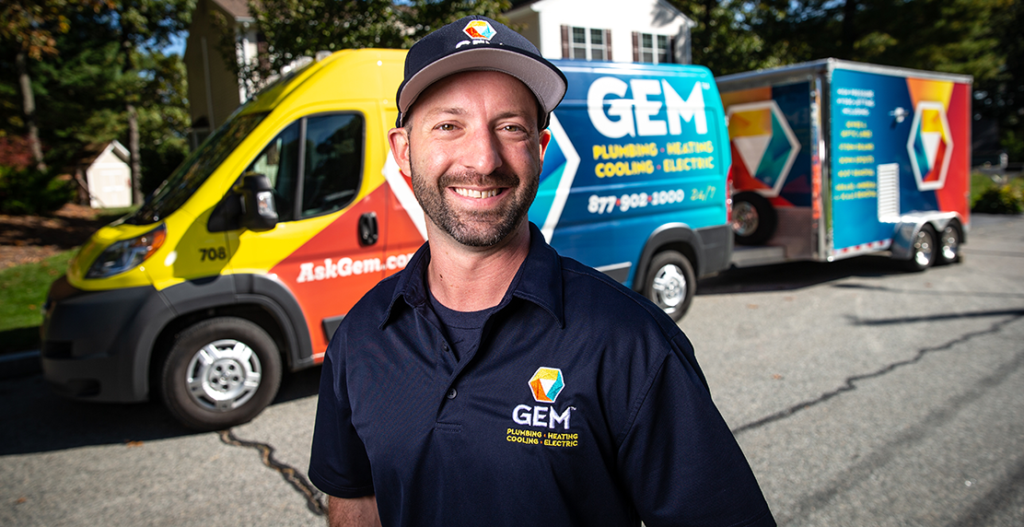 GEM Plumbing technician standing in front of branded service truck