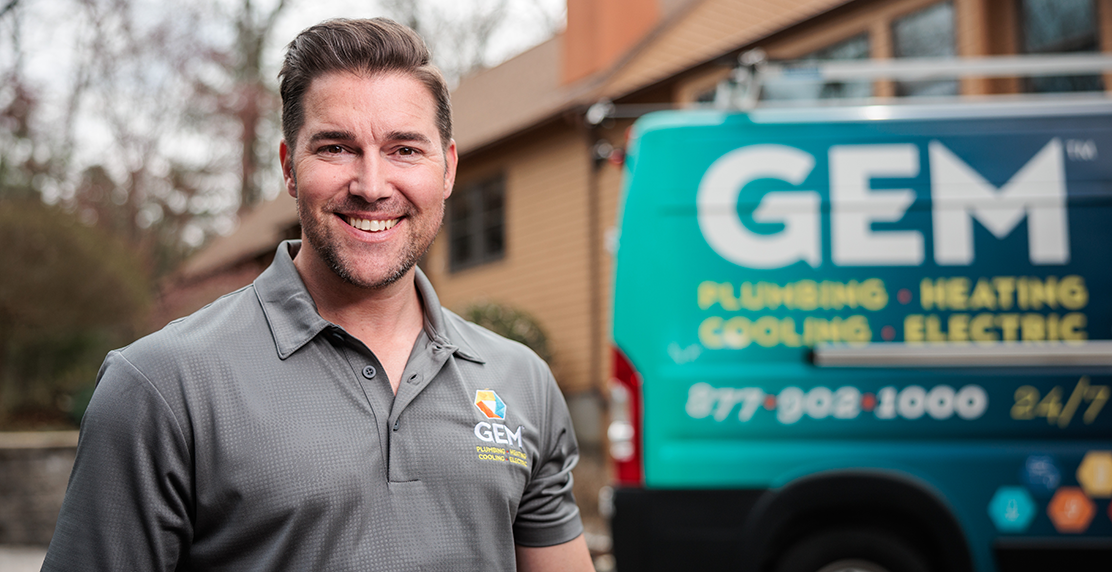 GEM Plumbing technician smiling in front of company van