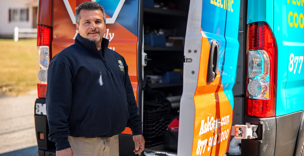 GEM Plumbing technician standing in front of branded service truck