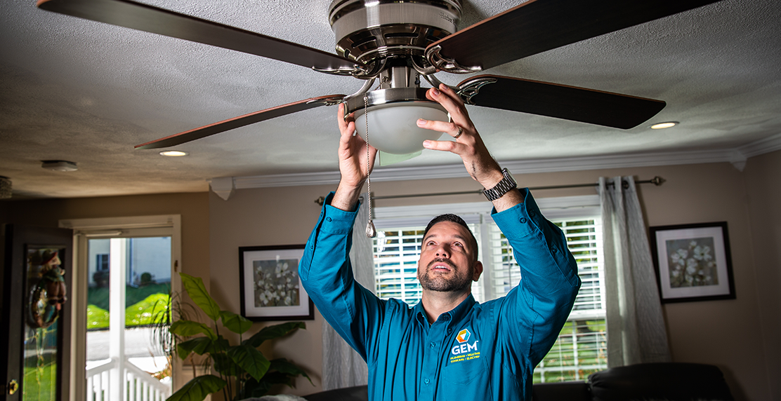 GEM HVAC technician installing ceiling fan indoors