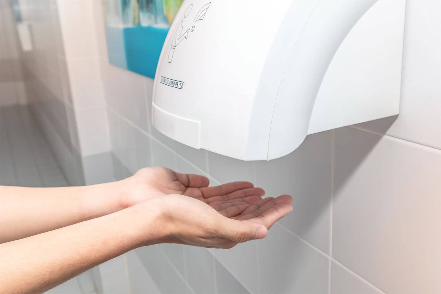 Person using touchless hand dryer in bathroom