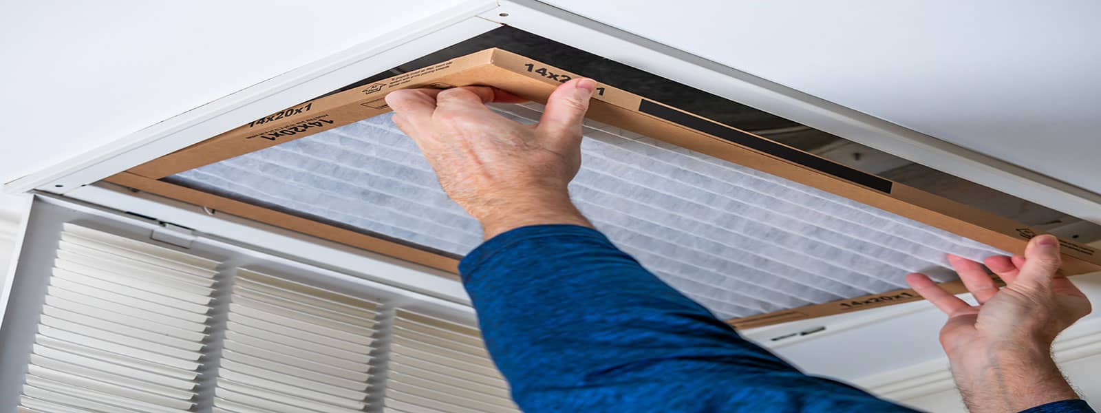 An HVAC technician fitting a filter in a vent
