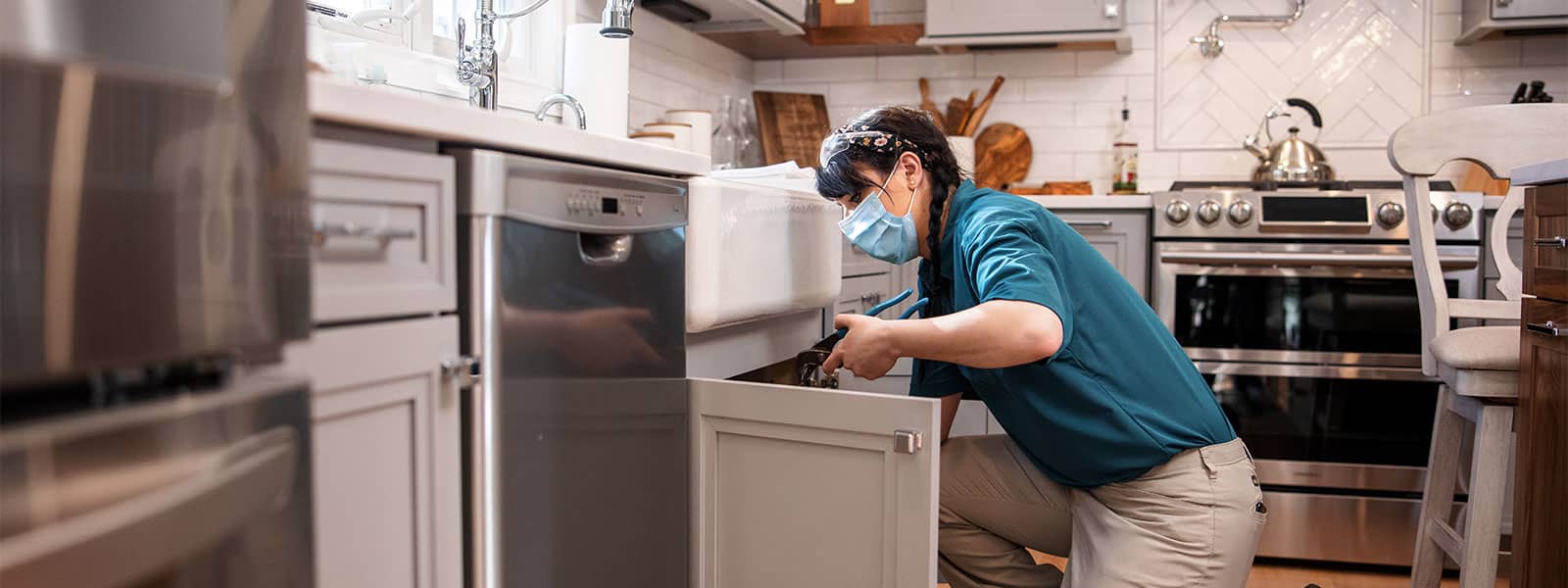 female plumber working on a kitchen sink drain