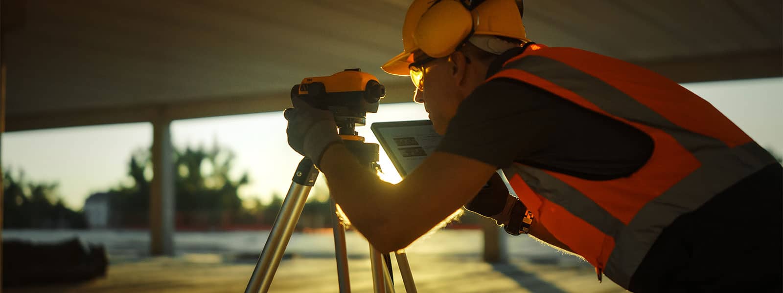 A construction worker holding a tablet and looking through a camera on a tablet