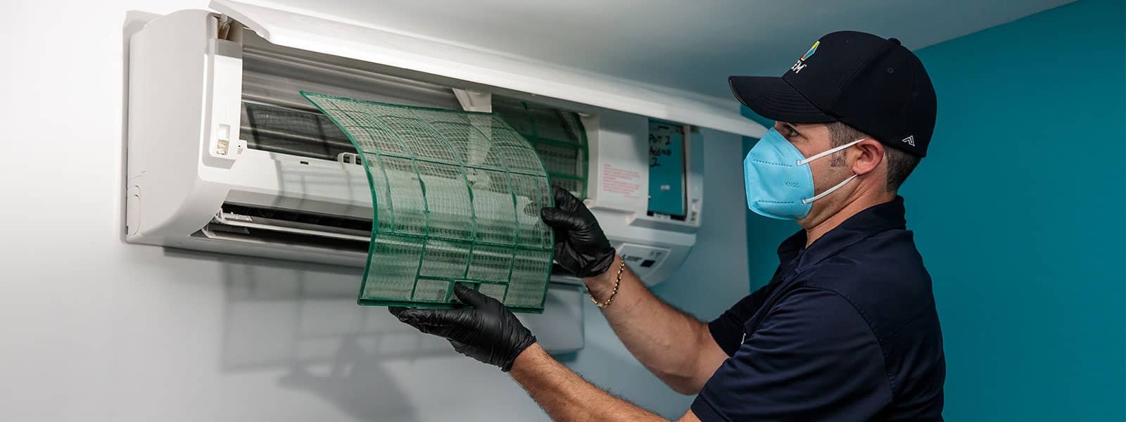 GEM technician changing mini-split unit filter with PPE