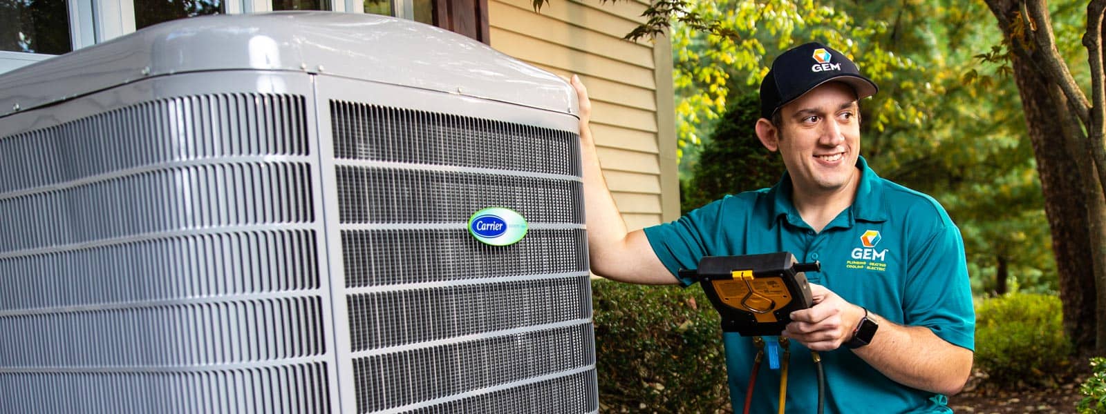 Happy GEM technician kneeling next to air conditioner