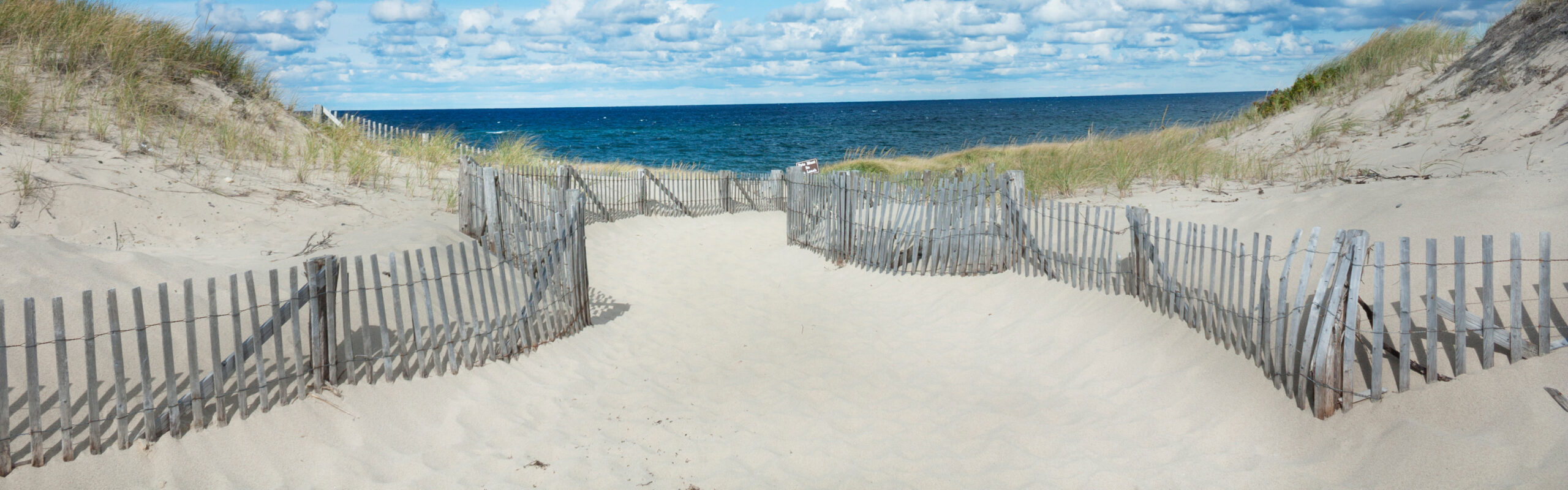 a fenced off beach path leading to the sea