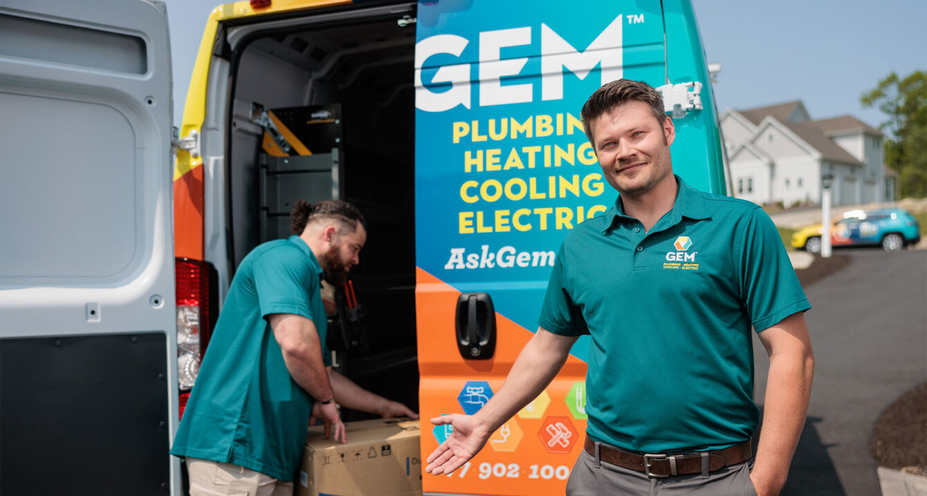 A GEM employee putting a box in a service truck and another employee pointing a him