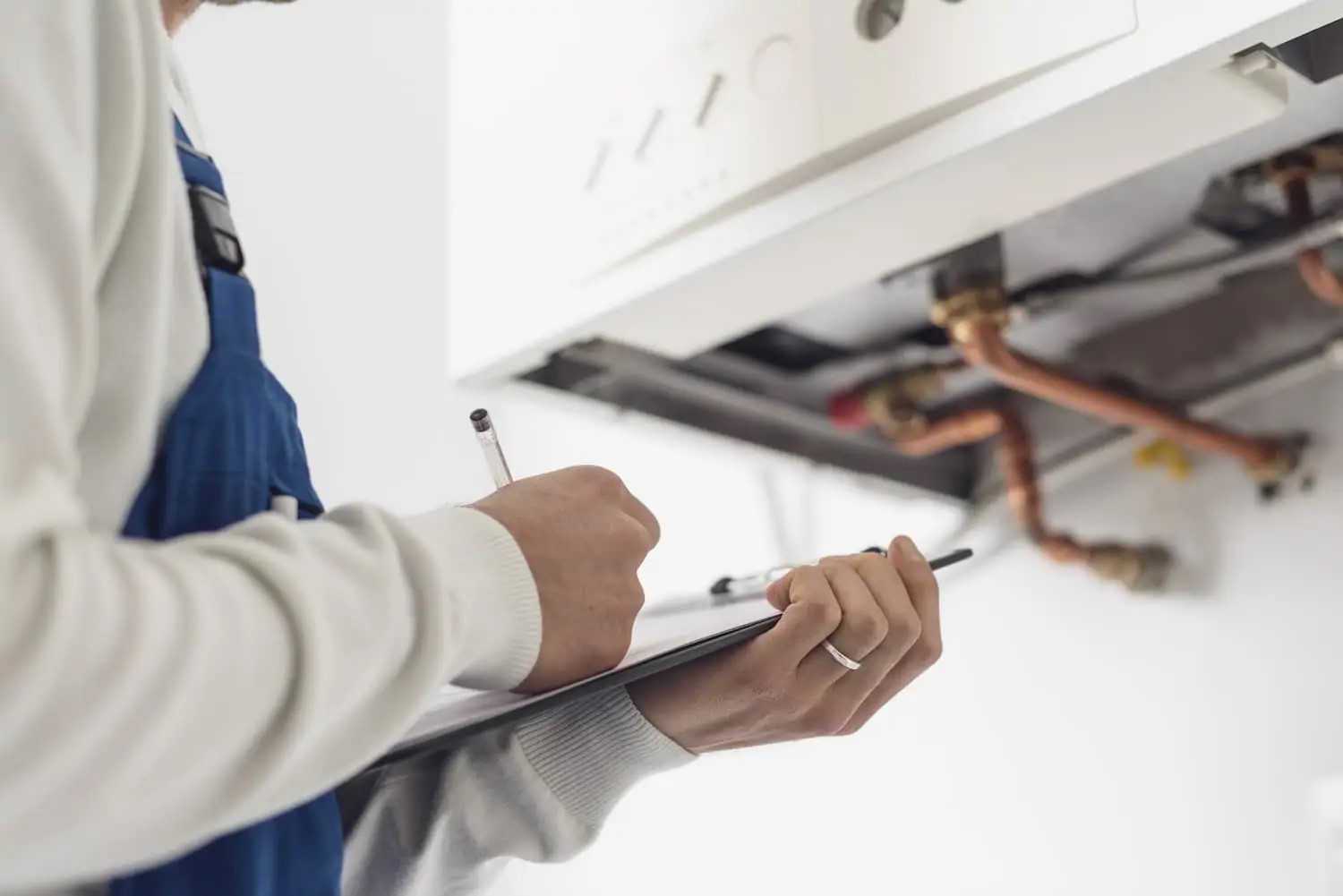 Close view of male plumber holding clipboard as he inspects a boiler.