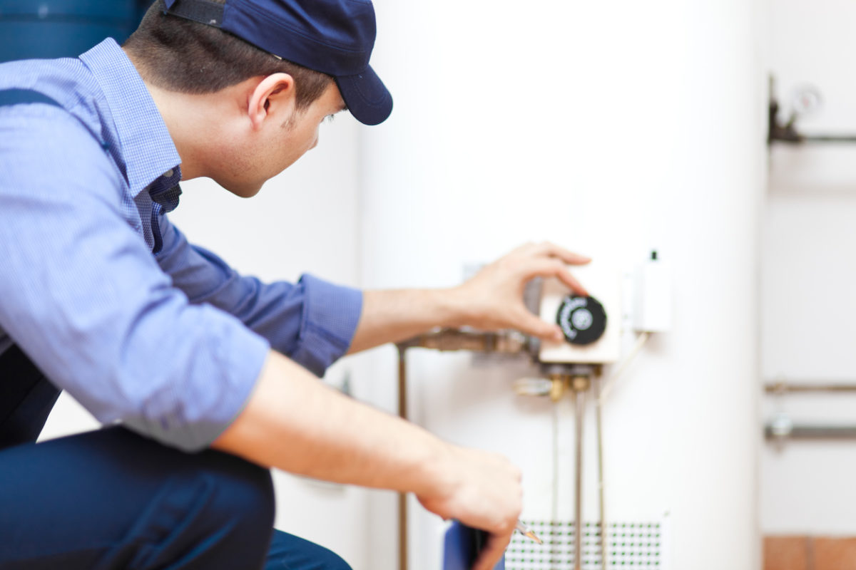 Male plumber inspecting a water heater.